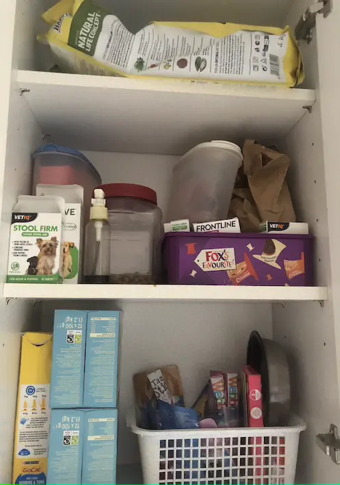 White kitchen cupboard with three shelves full of pet food and treats