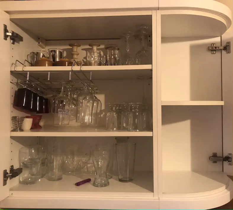 White kitchen cupboard with two shelves full of appliances and miscellaneous kitchen items