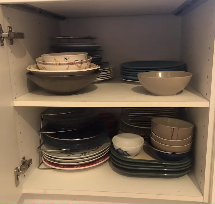 White kitchen cupboard with two shelves of plates and bowls