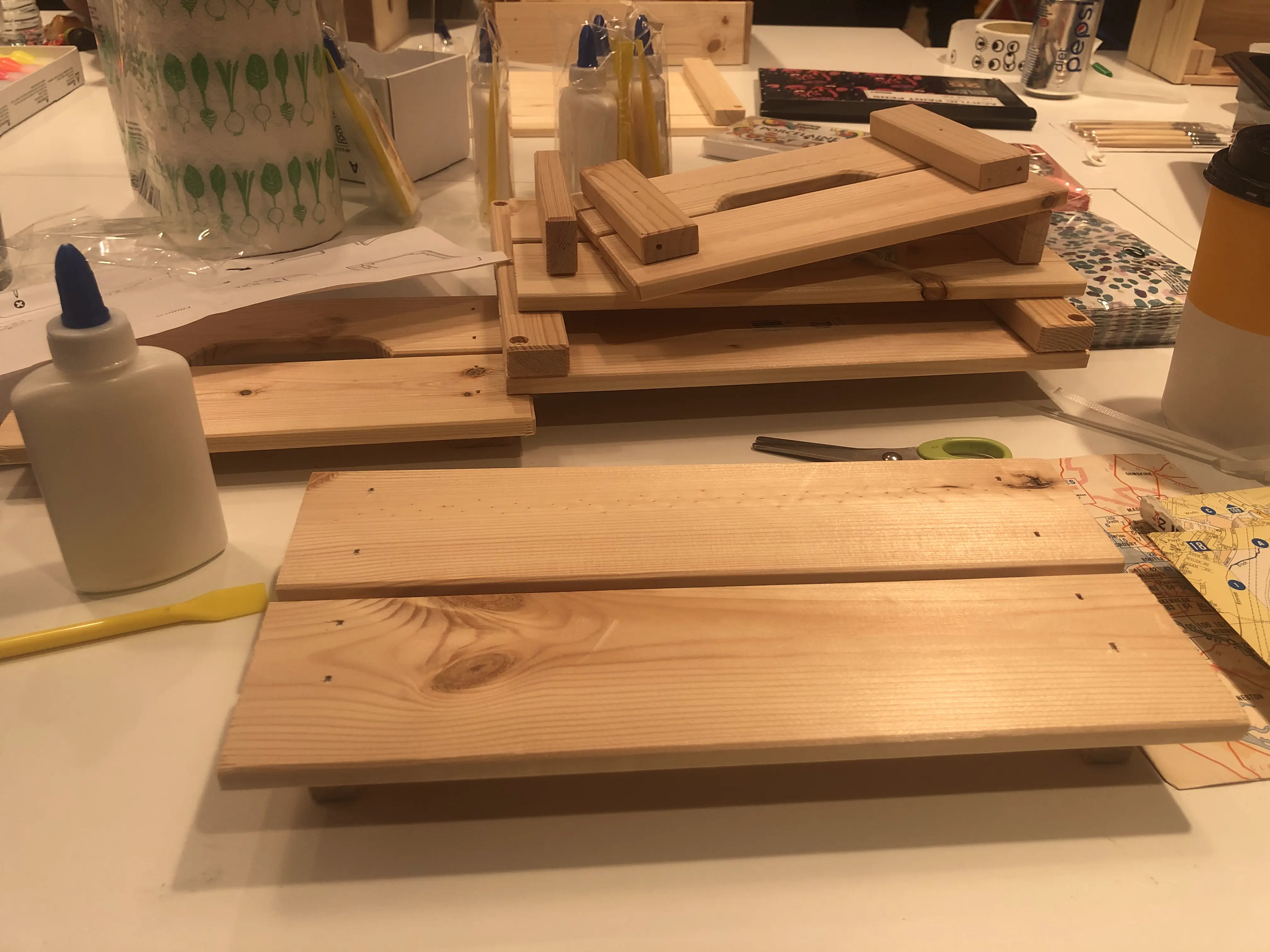 Pile of parts from a wooden crate on a table, with a glue bottle