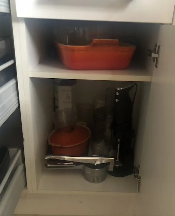 White kitchen cupboard with two shelves of bakeware and food mixers