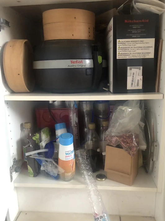 White kitchen cupboard with two shelves full of appliances and miscellaneous kitchen items