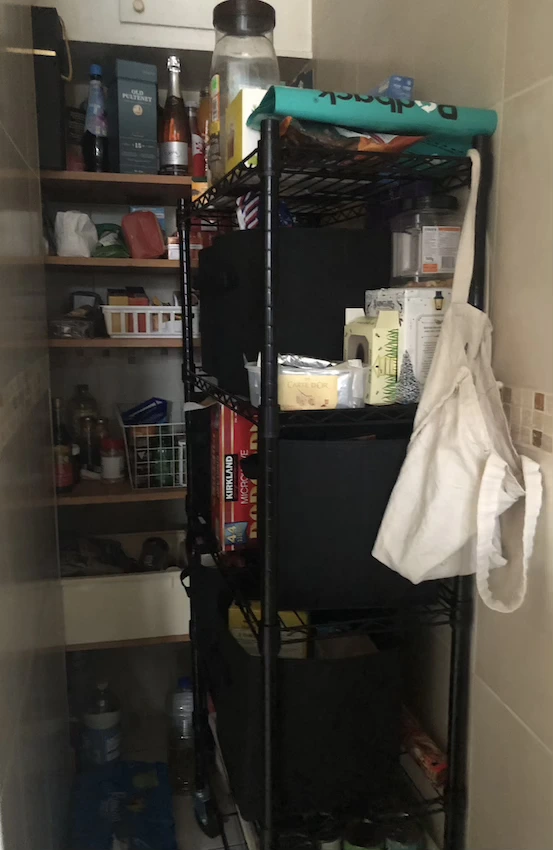 Two tall shelving units at right angles to each other, filled with wire baskets, boxes and foot items