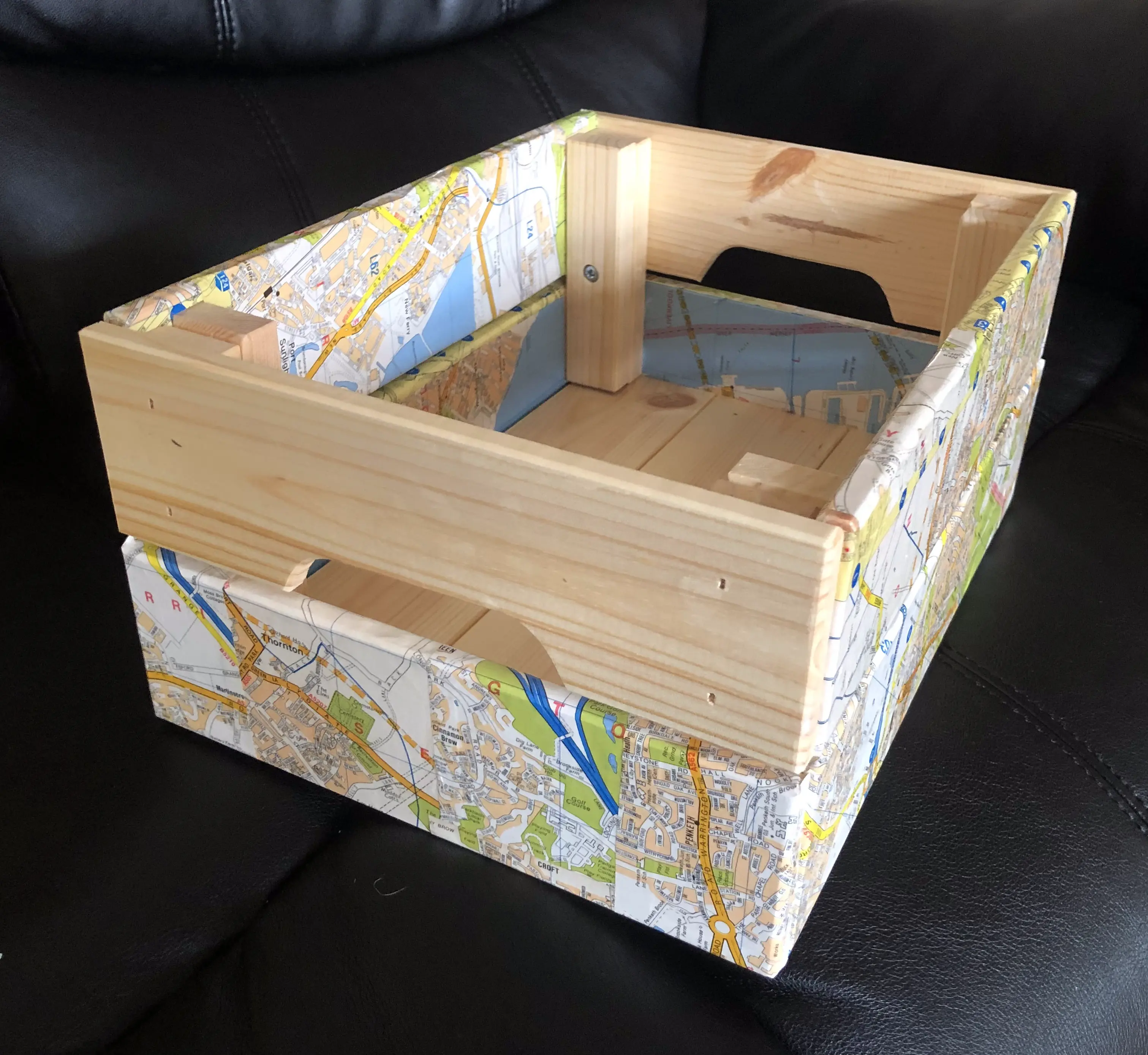 Wooden storage crate, with the sides and lower part of the ends covered in map paper