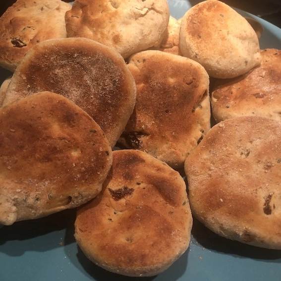 Pile of small round naan bread with raisins visible on a turquoise plate