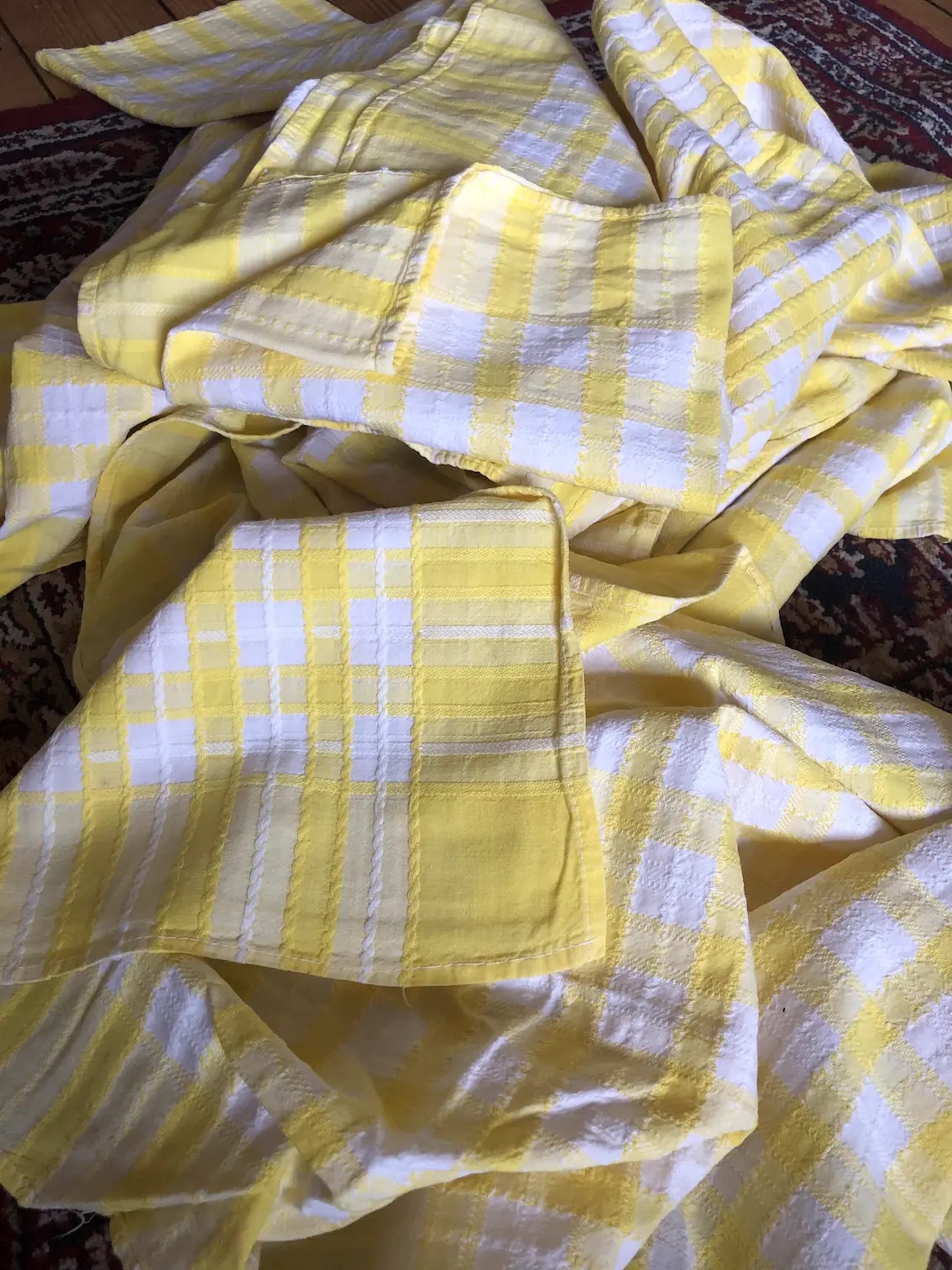 pile of folded, yellow and white checked tablecloths on a wooden floor