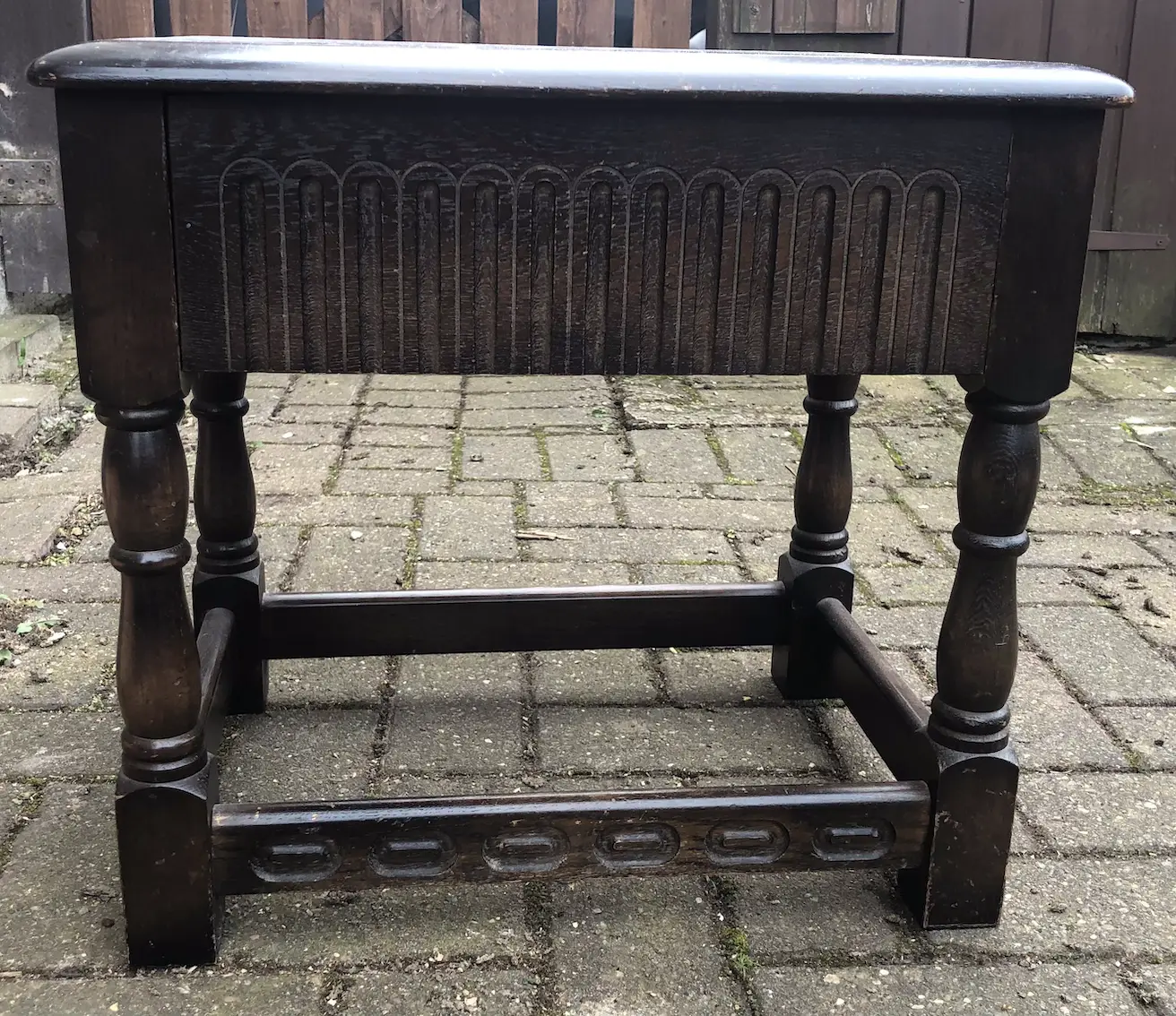 small dark brown table, with carved decoration, viewed from the side