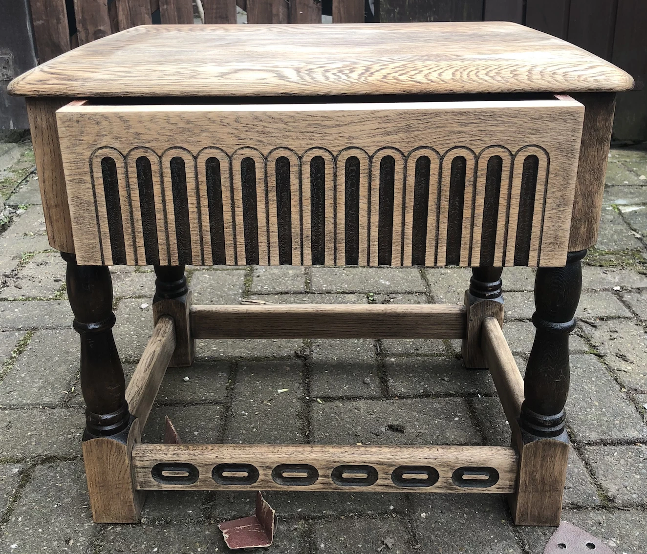 small wooden table, sanded to bare wood, with moulded detail and rounded legs covered in dark brown varnish