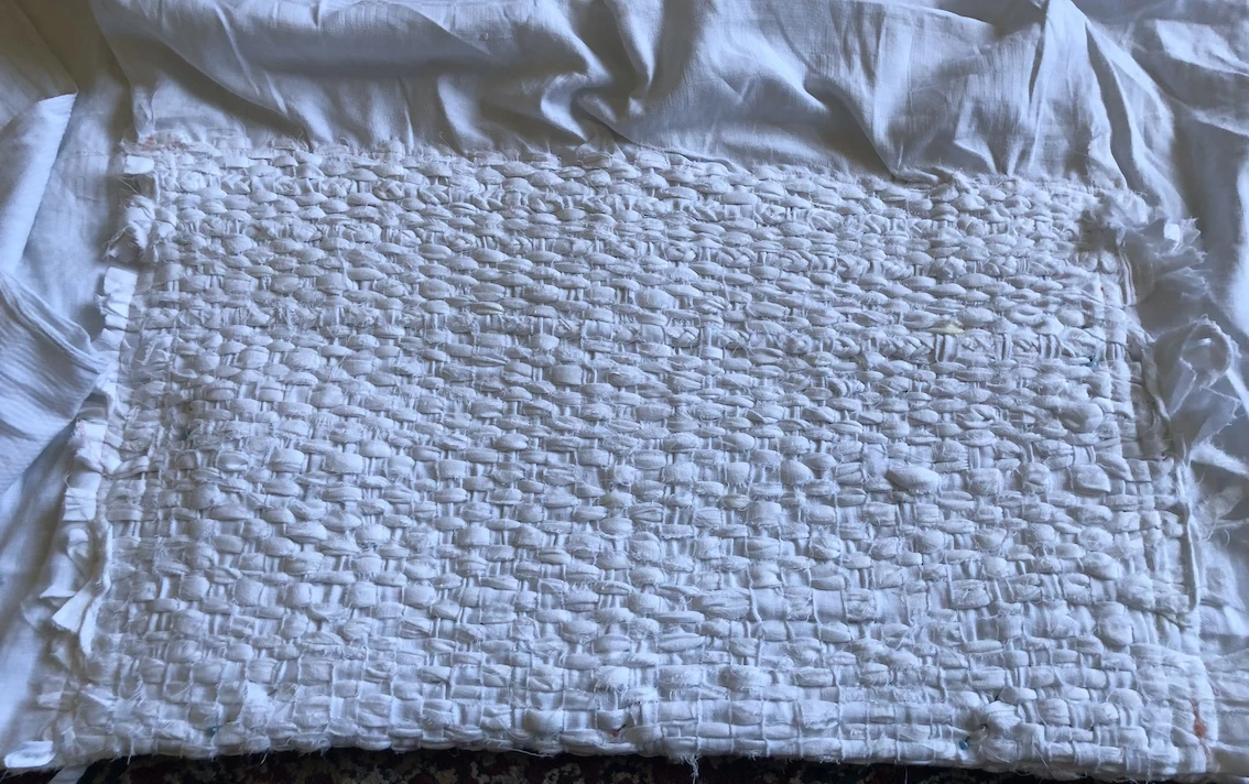 section of weaving using strips of white tablecloth fabric