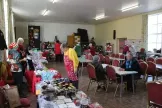 Church hall with tables and chairs in the centre and stalls around the edge in front of large windows