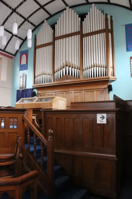 Organ pipes against a light blue wall with wooden panelled furnishings in front