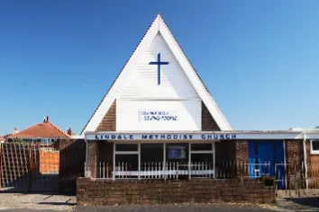 Modern brick built church with a steep, white trimmed A-frame roof