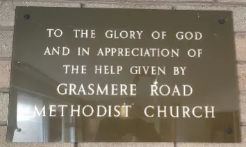 Brown perspex plaque with white lettered inscription to Grasmere Road Methodist Church commemorating the 1967 building of Lindale Methodist Church