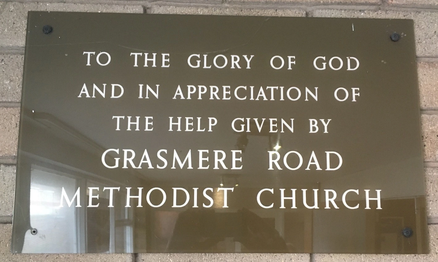 Brown perspex plaque with white lettered inscription to Grasmere Road Methodist Church commemorating the 1967 building of Lindale Methodist Church
