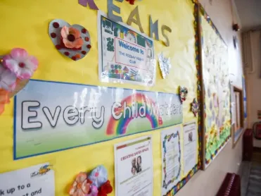 Yellow noticeboard displaying posters and decorative items