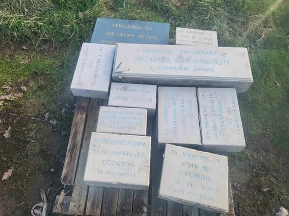 Assorted inscribed memorial stones piled on a wooden pallet