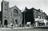 Exterior of a brick built church with square tower next to a bingo hall