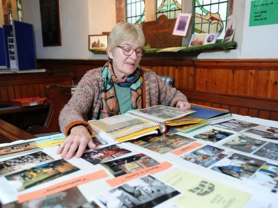 Heritage coordinator Diana Holden looking at table full of photographs
