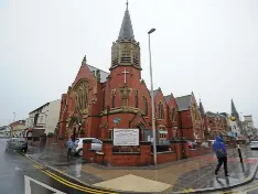 Exterior of a traditional red brick church with a spire