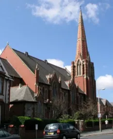 Angled view of a traditional red brick church with a spire