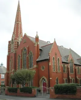 Front view of a traditional red brick church with a spire